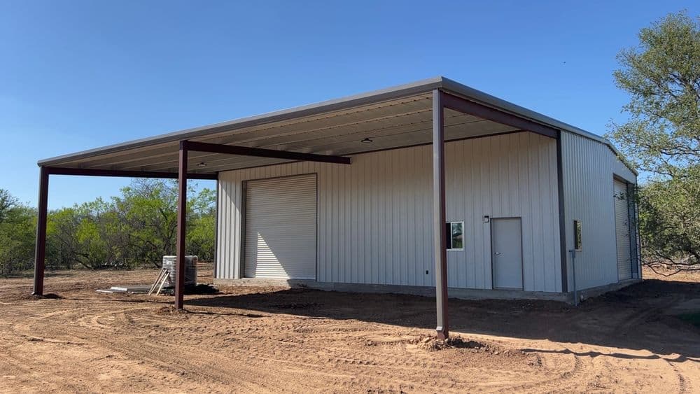 Metal storage building with a large overhang, located on a cleared plot of land.