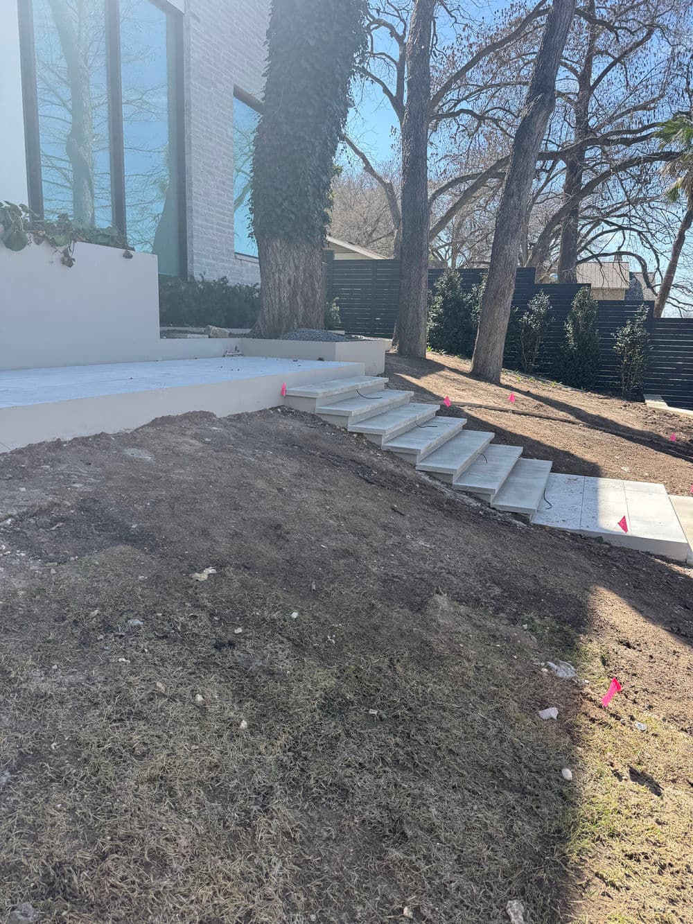 Newly constructed stone steps leading to a modern home surrounded by trees and landscaping.