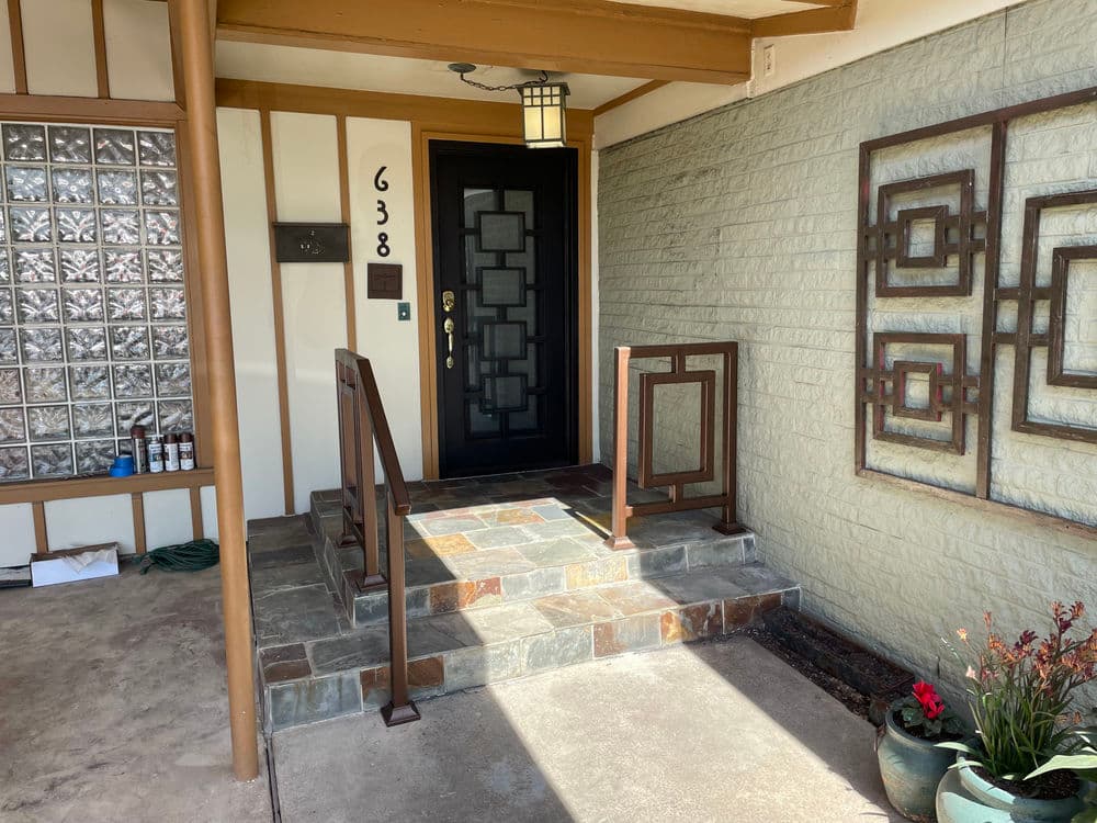 Modern entryway with stone steps, decorative railing, and landscaped planter at 638 address.