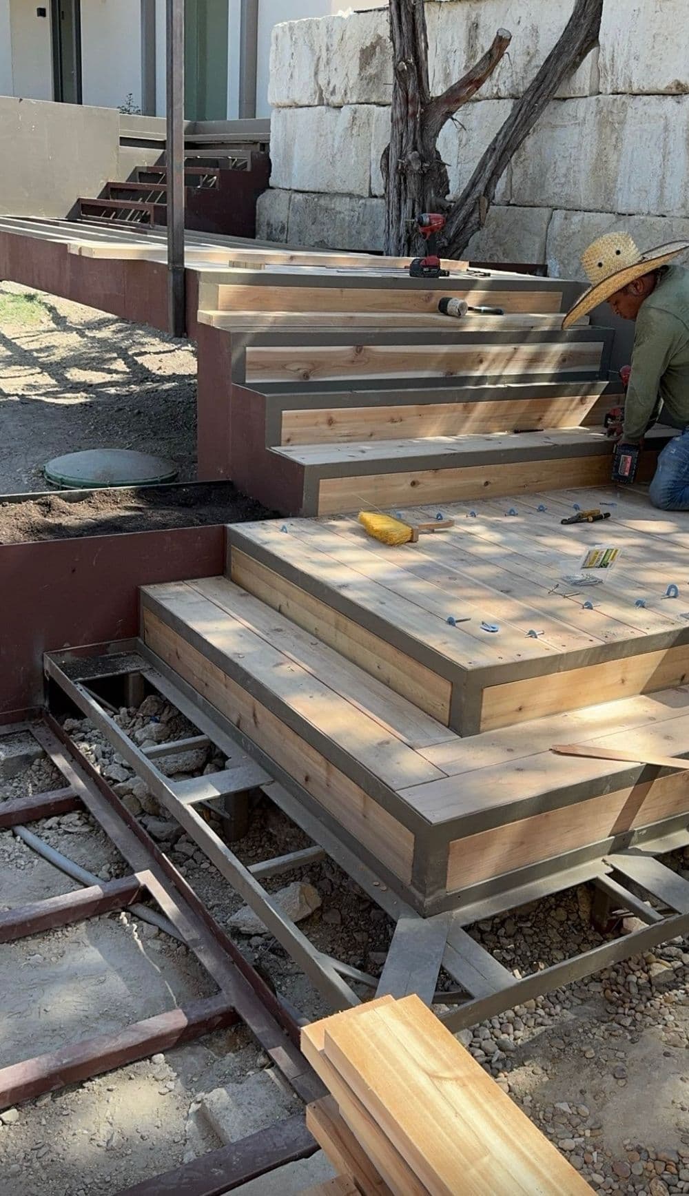 Person constructing modern wooden stairs with a metal framework in a residential setting.