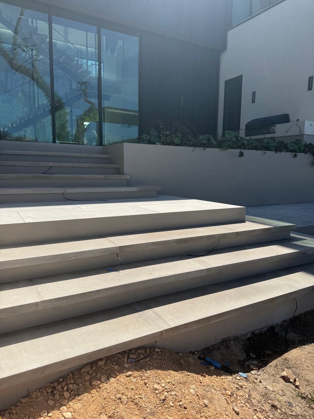Modern exterior stairs leading to a glass-walled entrance, with landscaping details visible.